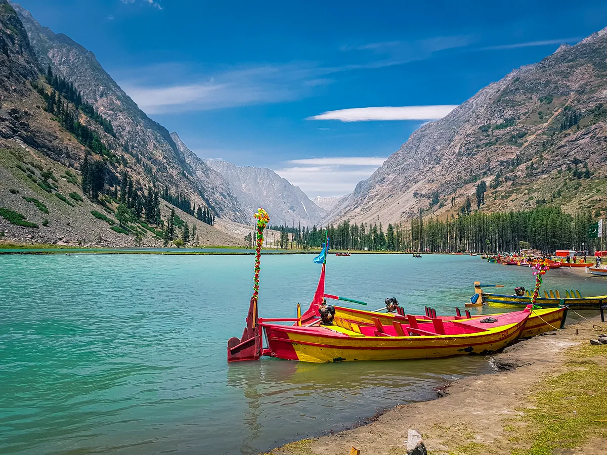 Painted wooden boats on the blue-green water of Mahodand Lake, ringed by pine forest in upper Swat